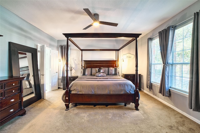 bedroom featuring ceiling fan, light carpet, and a textured ceiling