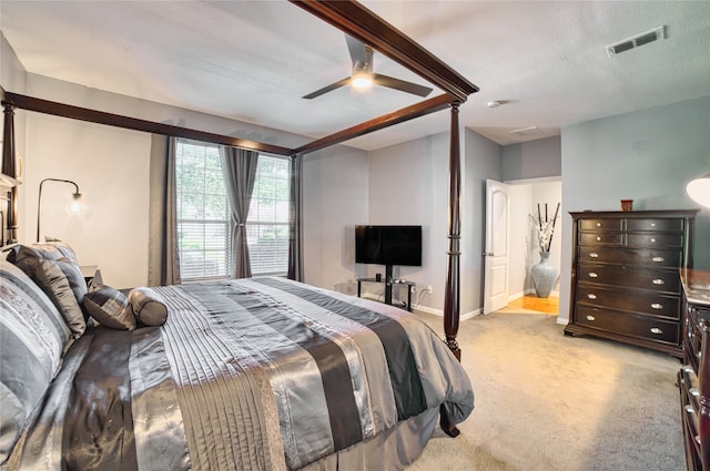 bedroom with a textured ceiling, ceiling fan, and light carpet