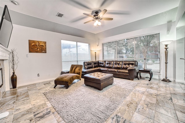 living room featuring a tile fireplace and ceiling fan