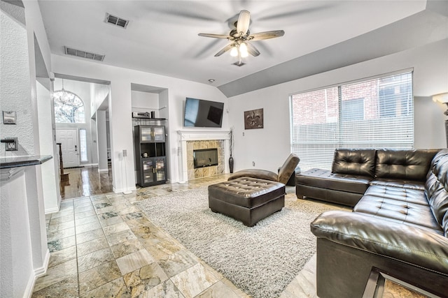 living room featuring ceiling fan, lofted ceiling, and a tile fireplace