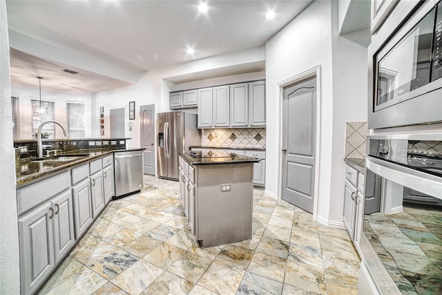 kitchen featuring sink, a center island, hanging light fixtures, gray cabinets, and appliances with stainless steel finishes