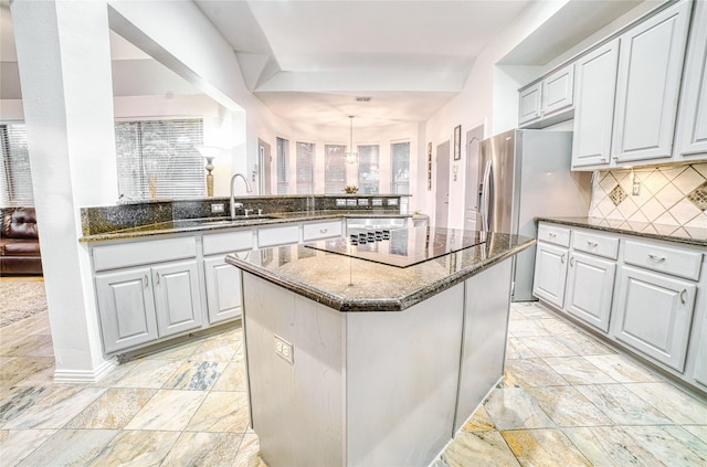 kitchen with backsplash, sink, hanging light fixtures, a kitchen island, and kitchen peninsula