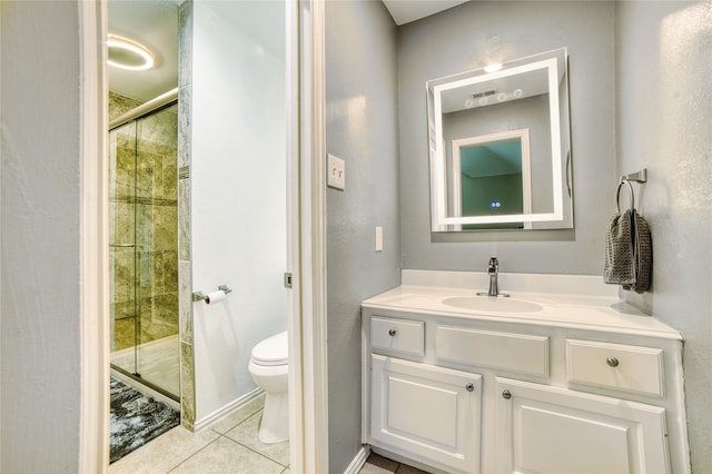 bathroom featuring tile patterned flooring, vanity, toilet, and a shower with shower door