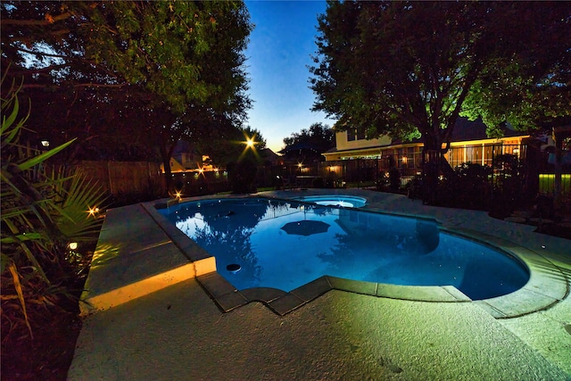 pool at dusk featuring an in ground hot tub