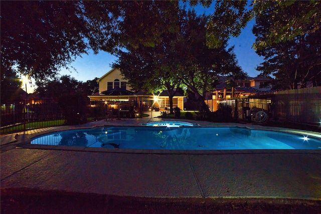 pool at dusk with an in ground hot tub