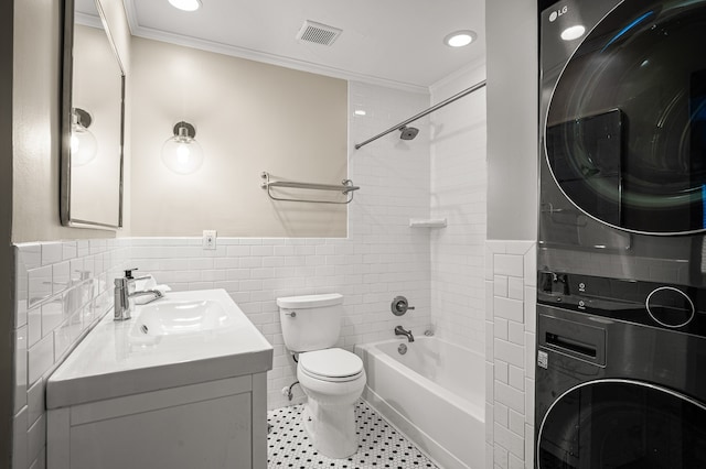 full bathroom featuring vanity, stacked washer and clothes dryer, tiled shower / bath combo, toilet, and ornamental molding