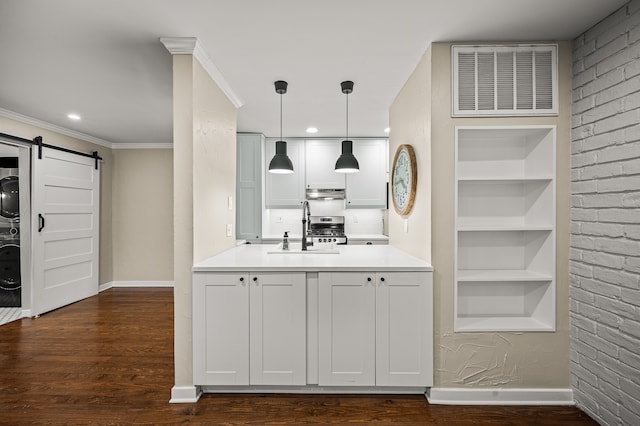 kitchen with white cabinets, dark hardwood / wood-style floors, a barn door, decorative light fixtures, and stacked washer / dryer