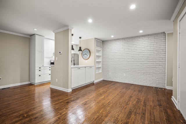 unfurnished living room featuring ornamental molding, sink, dark wood-type flooring, and brick wall