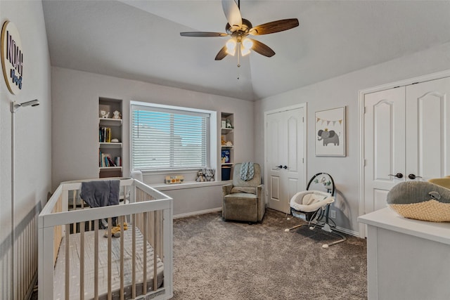 bedroom with carpet floors, a crib, lofted ceiling, and multiple closets