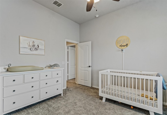 carpeted bedroom with ceiling fan and a crib