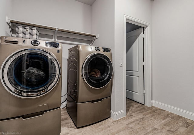 washroom with laundry area, light wood-style flooring, baseboards, and washing machine and clothes dryer