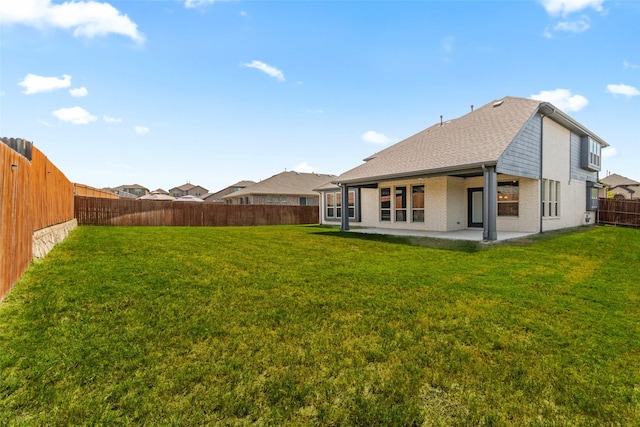 back of house featuring a patio, a fenced backyard, a shingled roof, a lawn, and brick siding