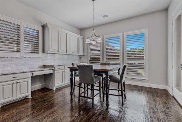 dining room featuring an inviting chandelier, dark hardwood / wood-style floors, and built in desk