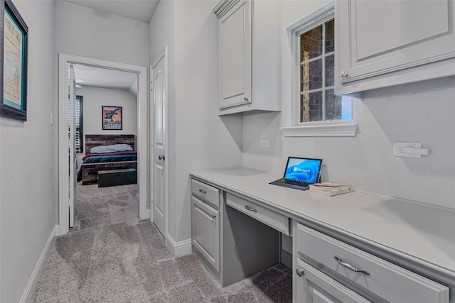 office area featuring built in desk, light colored carpet, and plenty of natural light