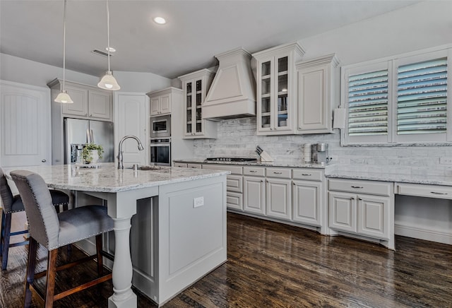 kitchen with pendant lighting, sink, a kitchen island with sink, stainless steel appliances, and custom range hood