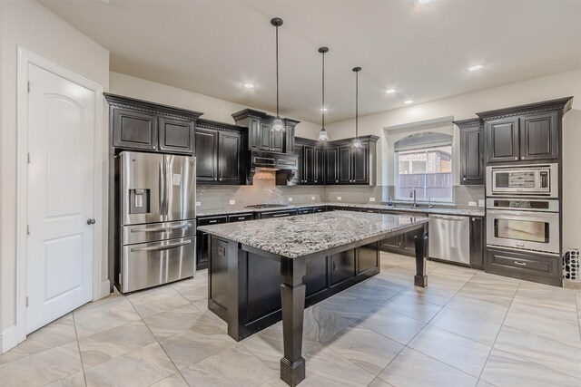 kitchen with tasteful backsplash, a kitchen bar, decorative light fixtures, a kitchen island, and appliances with stainless steel finishes