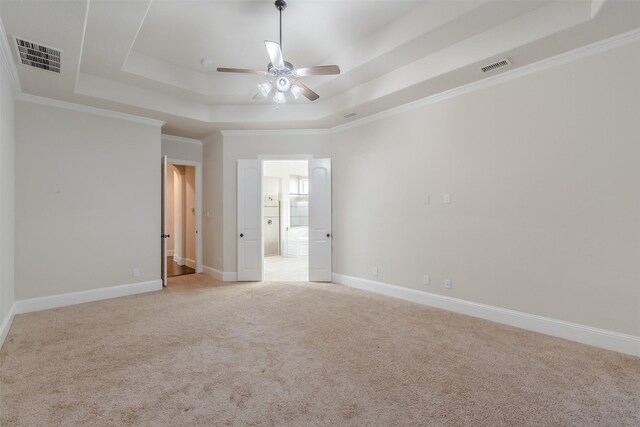 interior space with a raised ceiling, ceiling fan, ornamental molding, and light colored carpet