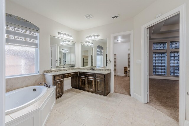 bathroom featuring tiled tub, vanity, and tile patterned flooring