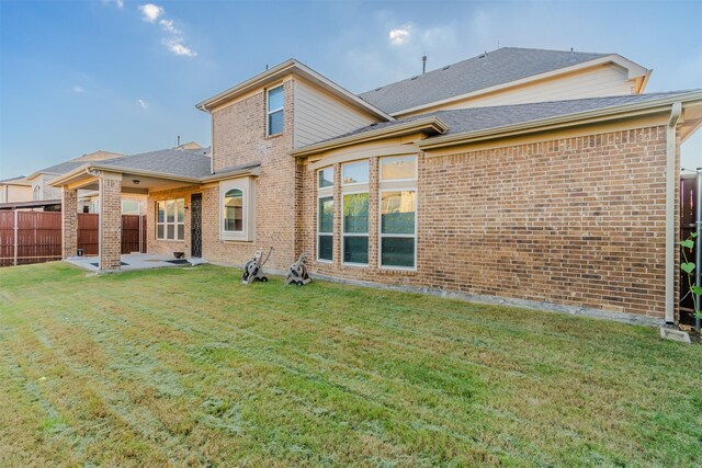 rear view of property featuring a lawn and a patio area