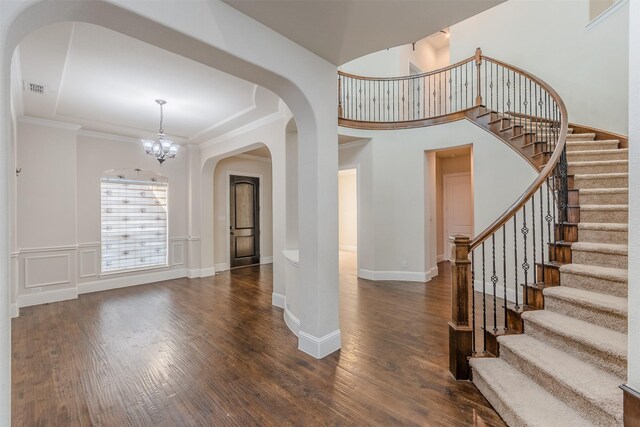 entryway featuring ornamental molding, dark wood-type flooring, and a notable chandelier