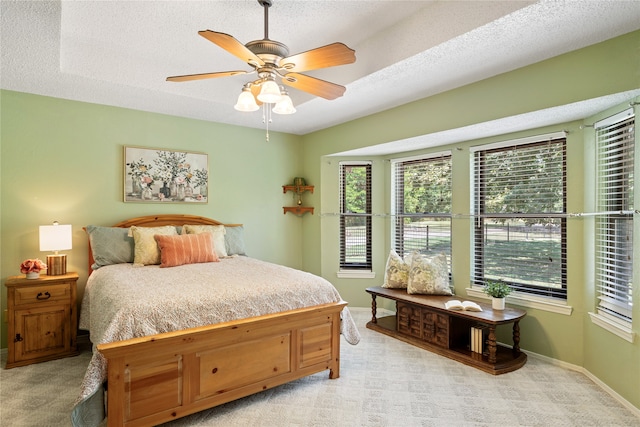 bedroom featuring light carpet, a textured ceiling, and ceiling fan