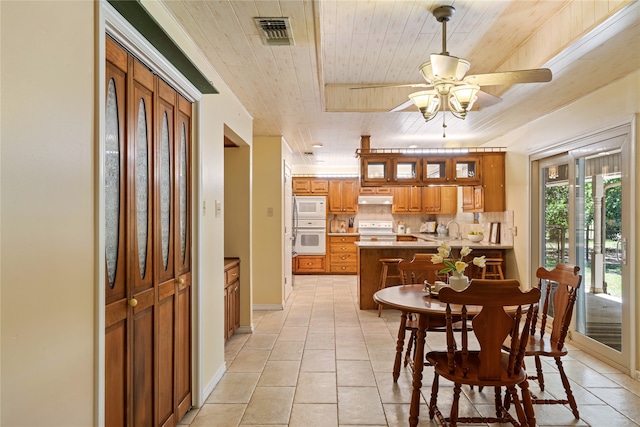 tiled dining space featuring ceiling fan, sink, and wooden ceiling