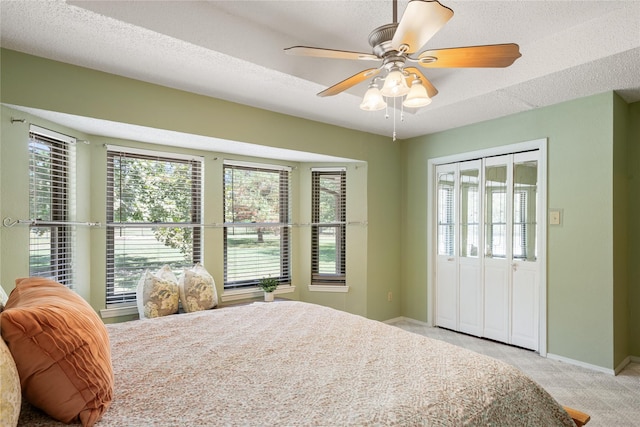 carpeted bedroom with multiple windows, ceiling fan, and a textured ceiling