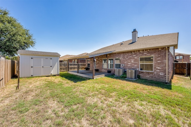 rear view of property with a storage shed, a yard, cooling unit, and a patio