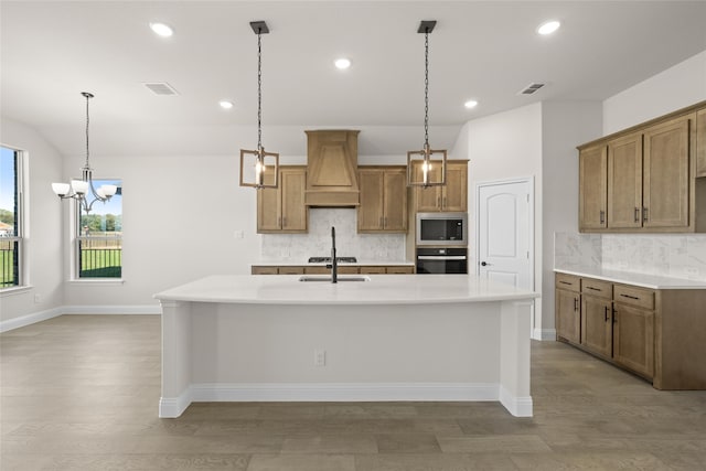 kitchen with tasteful backsplash, light hardwood / wood-style floors, a spacious island, custom range hood, and appliances with stainless steel finishes