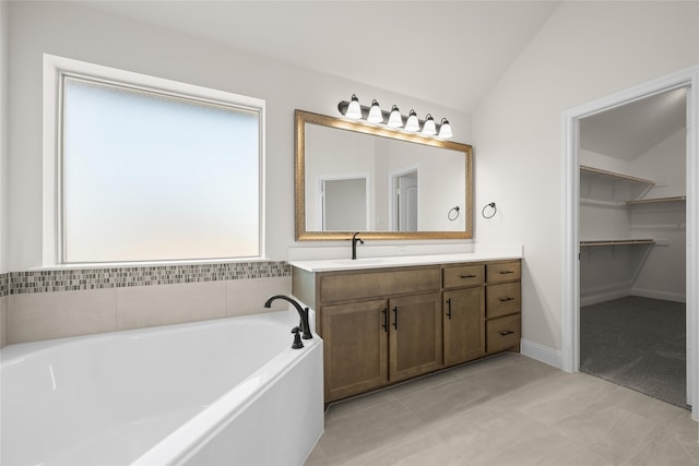 bathroom with tile patterned flooring, vanity, lofted ceiling, and a tub to relax in