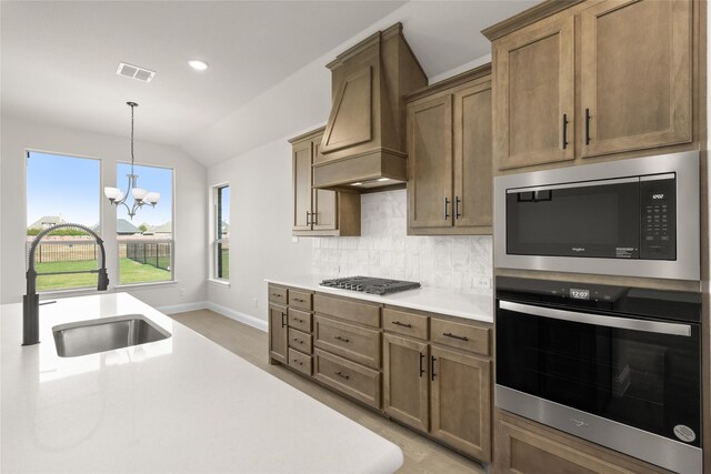 kitchen featuring custom exhaust hood, stainless steel appliances, sink, an inviting chandelier, and lofted ceiling