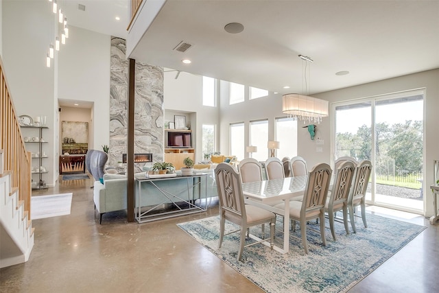 dining area with a notable chandelier, a large fireplace, and concrete flooring