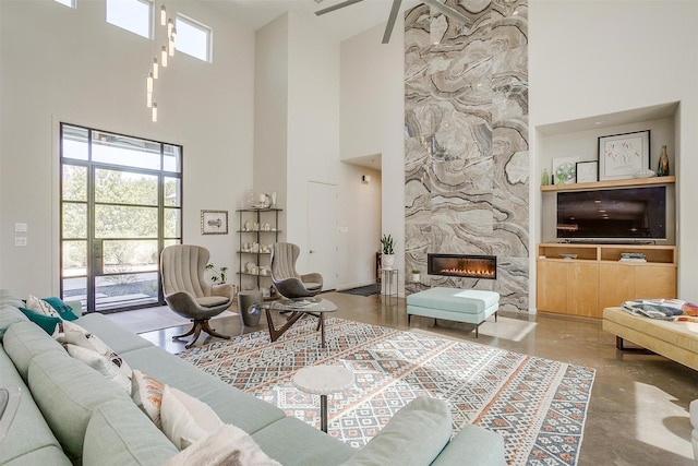 living room featuring a premium fireplace, a towering ceiling, and concrete flooring