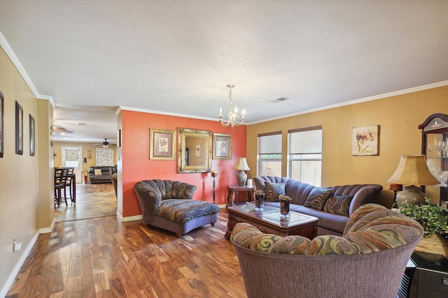 living room with ceiling fan with notable chandelier, hardwood / wood-style floors, and ornamental molding