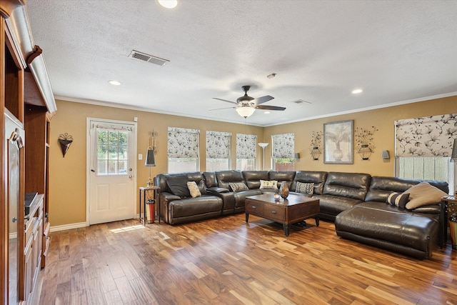 living room with a textured ceiling, ceiling fan, ornamental molding, and wood-type flooring