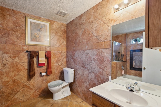 bathroom featuring a textured ceiling, tile patterned floors, vanity, tile walls, and toilet