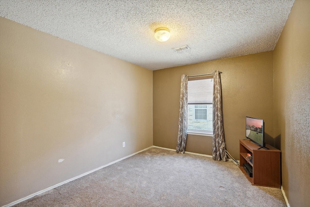 unfurnished room featuring light carpet and a textured ceiling