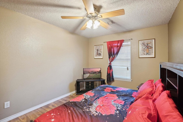 bedroom featuring ceiling fan, hardwood / wood-style floors, and a textured ceiling