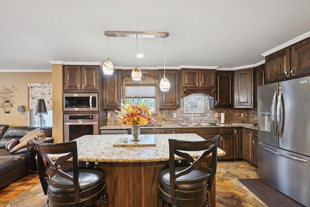 kitchen featuring light stone countertops, appliances with stainless steel finishes, decorative light fixtures, dark brown cabinets, and crown molding