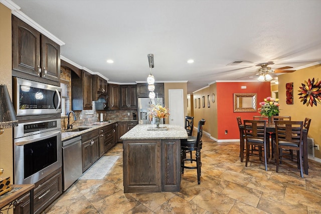 kitchen featuring a center island, stainless steel appliances, sink, hanging light fixtures, and backsplash