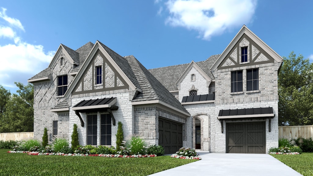 tudor home featuring a garage and a front lawn