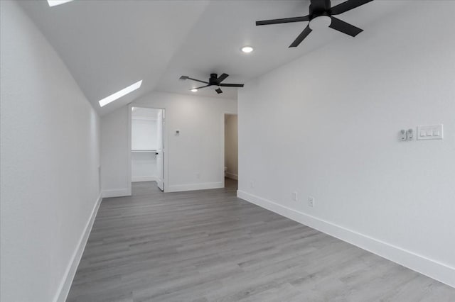 interior space with ceiling fan, vaulted ceiling with skylight, and light hardwood / wood-style floors