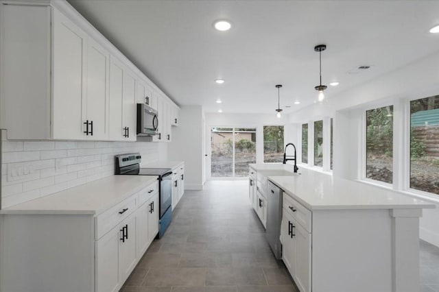 kitchen featuring sink, an island with sink, decorative light fixtures, white cabinetry, and stainless steel appliances