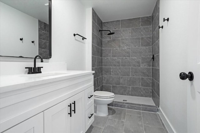 bathroom featuring a tile shower, vanity, and toilet