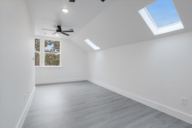 bonus room featuring ceiling fan, hardwood / wood-style floors, and lofted ceiling with skylight