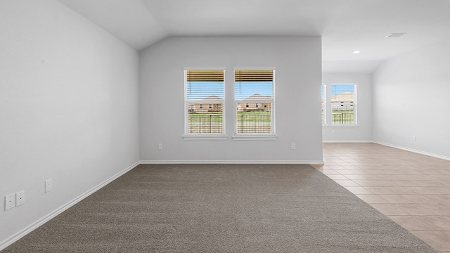 empty room with lofted ceiling and light tile patterned floors