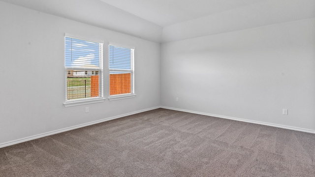 carpeted spare room featuring lofted ceiling