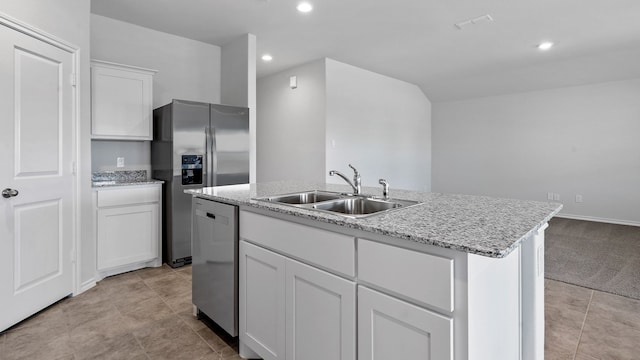 kitchen featuring a kitchen island with sink, stainless steel appliances, sink, light stone counters, and white cabinets