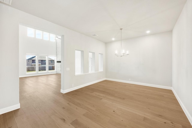 spare room with an inviting chandelier and light wood-type flooring