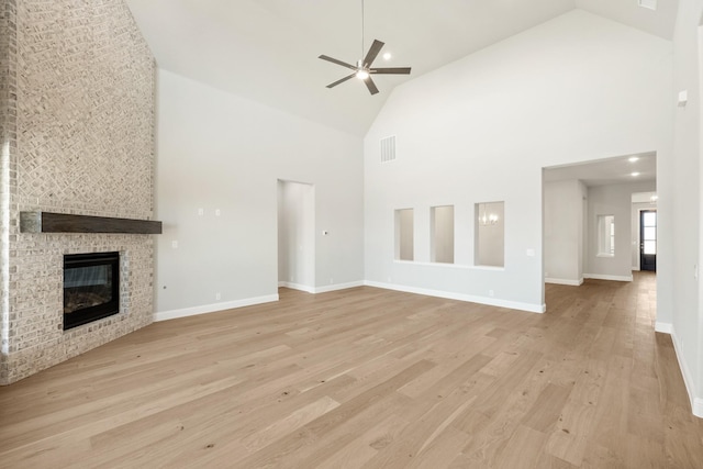 unfurnished living room with ceiling fan, a fireplace, high vaulted ceiling, and light hardwood / wood-style flooring